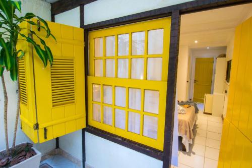 a yellow door in a room with a bedroom at Chez Pitu Praia Hotel in Búzios