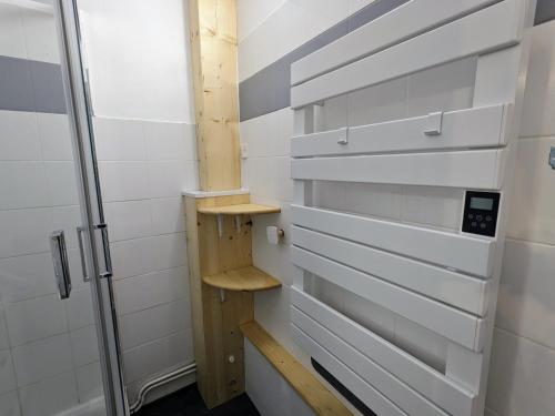 ducha a ras de suelo con paredes blancas y estanterías de madera en Appartement 4 personnes et jardin, en Bielle