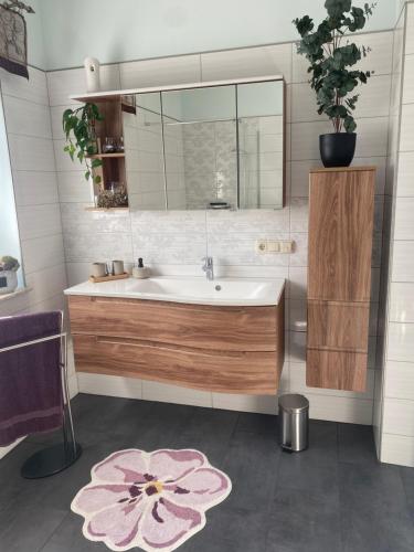 baño con lavabo, espejo y alfombra de flores en Ferienhaus Albertus en Cottbus