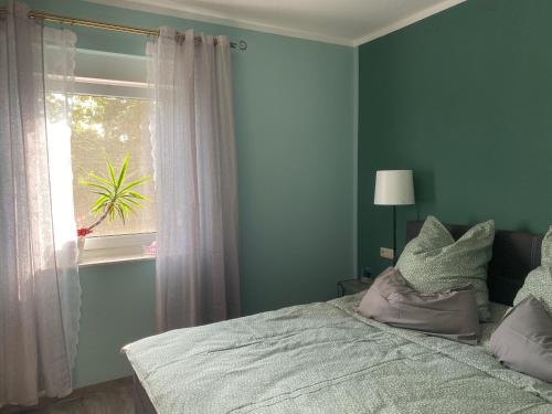 1 dormitorio con paredes verdes y 1 cama con ventana en Ferienhaus Albertus en Cottbus