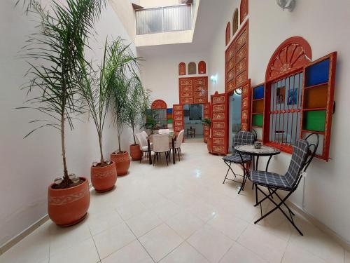 ein Wohnzimmer mit Pflanzen, Tischen und Stühlen in der Unterkunft Riad Maya in Rabat