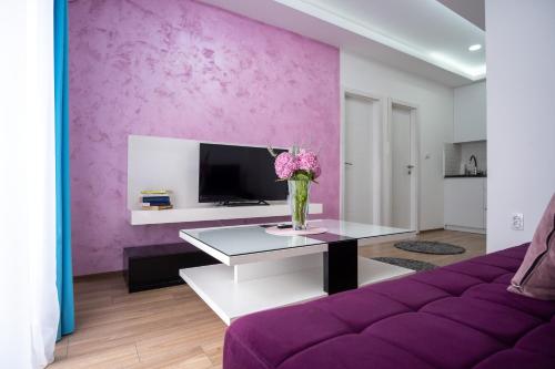 a living room with purple walls and a vase of flowers on a table at Apartments Sweet Dreams in Trebinje