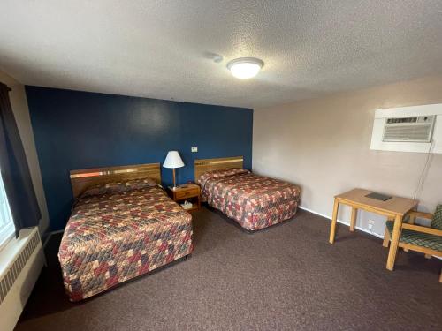 Cette chambre comprend 2 lits et une table. dans l'établissement The Village Motel, à Steamboat Rock