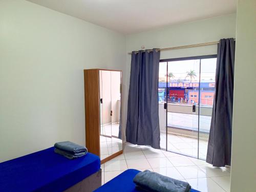 a bedroom with a blue bed and a large window at Lindo Apto102 em Primavera do Leste in Primavera do Leste