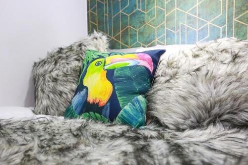 uma almofada colorida de pássaro sentada num sofá em A102 Cheery Bright Loft em Coventry