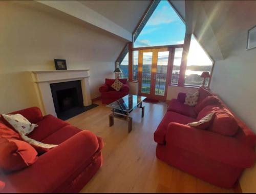 a living room with two red couches and a fireplace at The Lake House in Drumshanbo