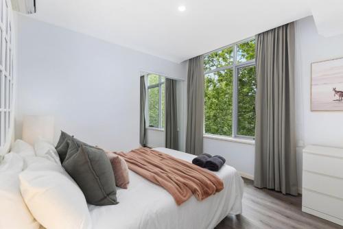 a white bedroom with a large bed and windows at Royal Respite Spacious Apartment - Walk to Restaurants in Perth