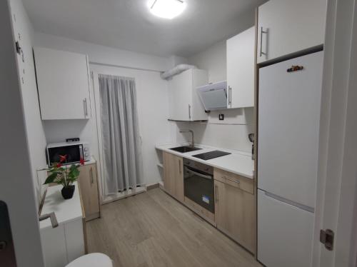 una pequeña cocina con armarios blancos y nevera. en apartamento con jacuzzi, El Rincón de Ayud, en Calatayud