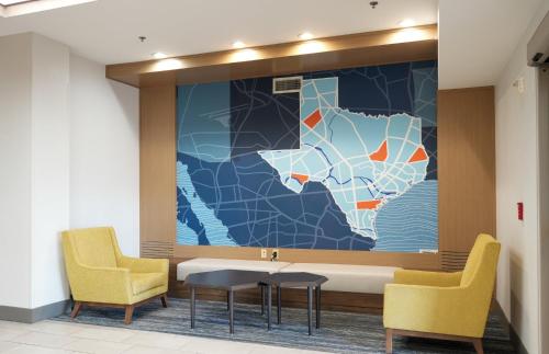 a wall mural in a waiting room with two chairs and a table at Holiday Inn Express Hotel & Suites Cedar Hill by IHG in Cedar Hill