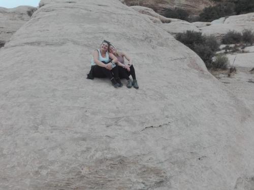 two women sitting on a rock in the desert at - Trekking from Dana to Petra in Dana