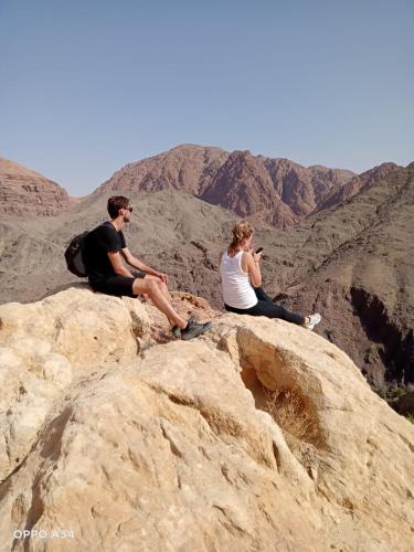a man and woman sitting on top of a mountain at - Trekking from Dana to Petra in Dana