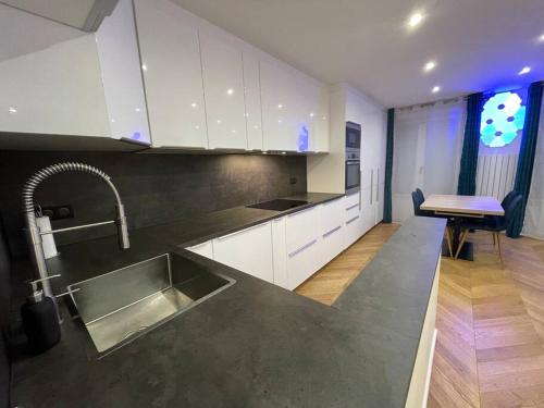 uma cozinha com um lavatório de aço inoxidável e armários brancos em Appartement moderne de 2 pièces em Suresnes