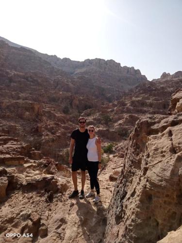 a man and woman standing on a rock in a canyon at - Trekking from Dana to Petra in Dana