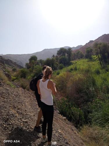 a woman walking down a dirt road at - Trekking from Dana to Petra in Dana