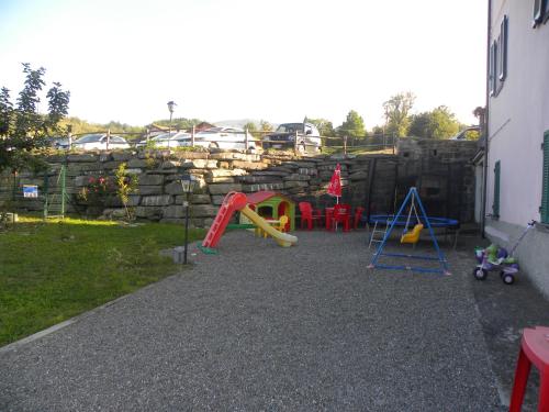a backyard with a playground with a rock wall at La Castagna Matta in Albareto