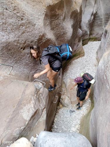 two people are climbing through a rock canyon at - Trekking from Dana to Petra in Dana