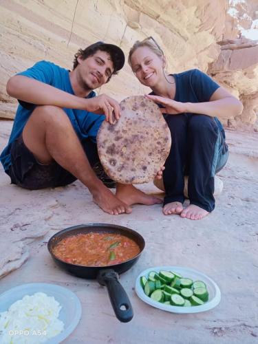 a man and woman sitting next to a pot of food at - Trekking from Dana to Petra in Dana