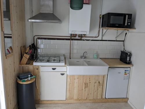 Una pequeña cocina con fregadero y estufa. en zomerhuis in Wijk aan Zee! 2 pers, en Wijk aan Zee