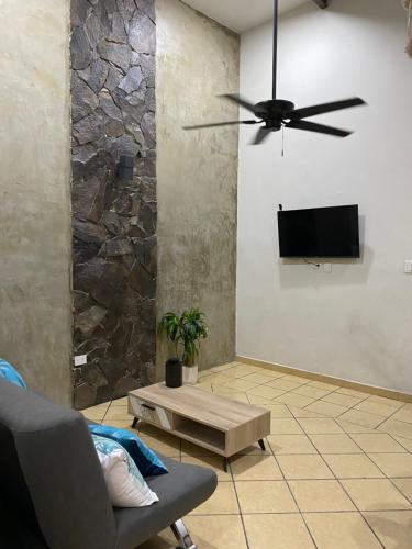 a living room with a ceiling fan and a tv at Departamento catalina in Mérida