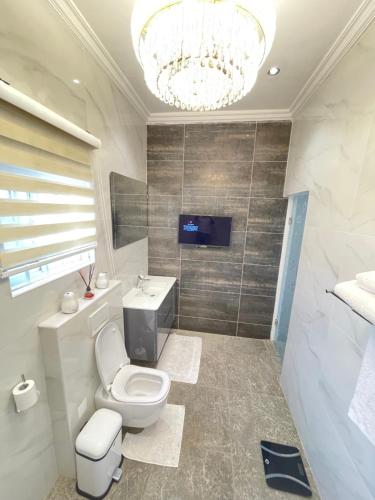 ein Badezimmer mit einem WC, einem Waschbecken und einem Kronleuchter in der Unterkunft Gold Flat in Accra