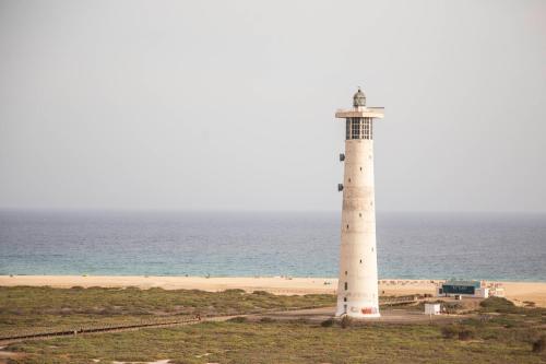 a lighthouse on the beach near the ocean at The Sunny Flair, Relaxing Experience in Morro del Jable