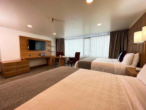 a hotel room with two beds and a flat screen tv at Wyndham Garden Quito in Quito
