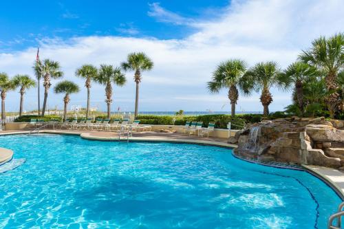 a swimming pool with palm trees in a resort at Jade East Towers 1050 by Newman-Dailey in Destin