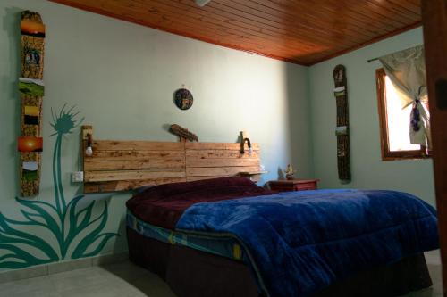 a bedroom with a bed with a wooden headboard at Acusi Hostel Camping in Humahuaca