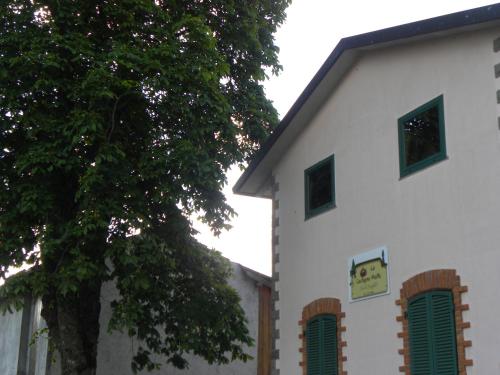 a white building with green windows and a clock on it at La Castagna Matta in Albareto