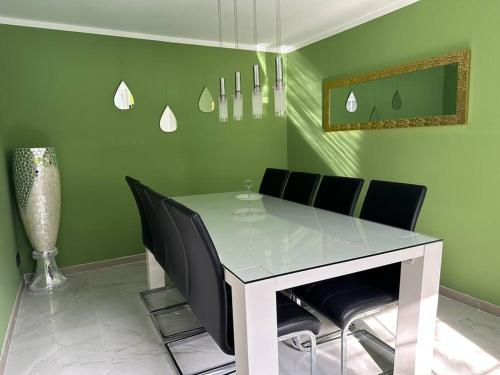 Outlet Center House, Pool-Jacuzzi-Garden-Sundeck في بارندورف: غرفة طعام خضراء مع طاولة بيضاء وكراسي سوداء