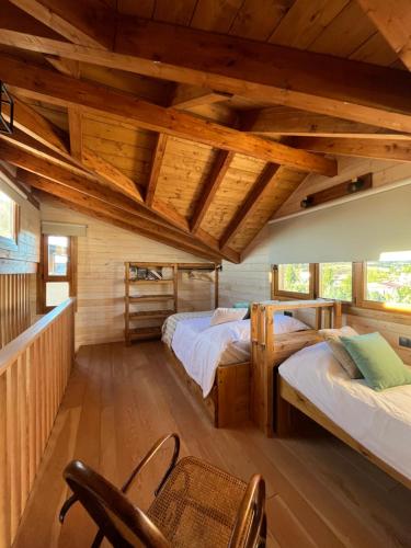 a log cabin bedroom with two beds and a chair at Luxury Rural Cuenca in Cuenca