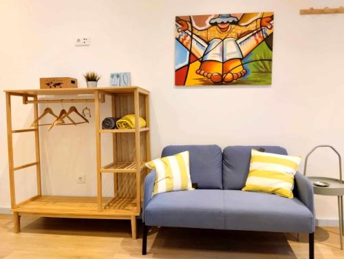 a living room with a blue couch and a painting on the wall at Maria Surfista_ As Três Marias in Matosinhos
