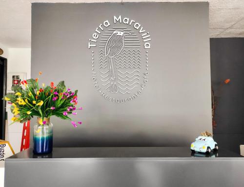 a sign on a wall with flowers in a vase at Tierra Maravilla in Salento