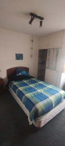 1 dormitorio con 1 cama con edredón a rayas en Habitación individual, baño compartido, en Santiago