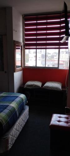 Habitación con 2 camas y ventana con persianas. en Habitación individual, baño compartido, en Santiago