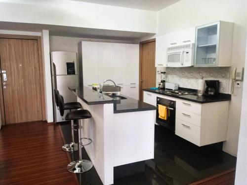 a kitchen with white cabinets and black counter tops at High-Rise Reforma Apartment , 2BDR, 2BATH, in Mexico City