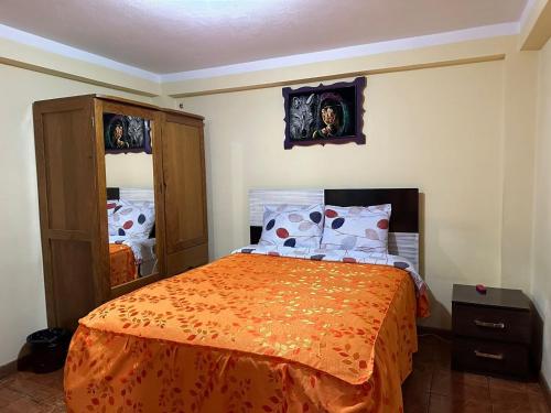 a bedroom with a bed with an orange bedspread at Hospedaje Qorichaska's in Cusco