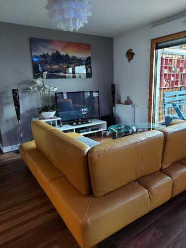 ein Wohnzimmer mit einem braunen Sofa und einem Tisch in der Unterkunft Stade de France Chambre d'Hôte by RESERVATI HOME in Saint-Denis