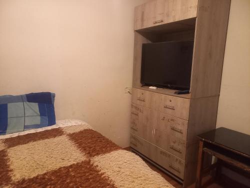 een slaapkamer met een televisie en een dressoir met een bed bij MyD in Cuzco