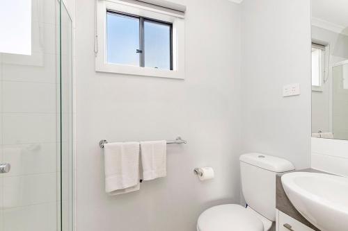 a white bathroom with a toilet and a sink at Portland Holiday Village in Portland