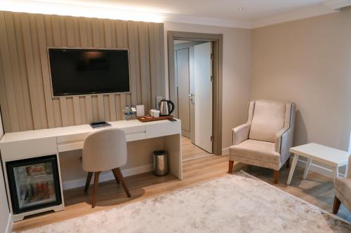 a room with a desk and a chair and a television at Vira Otel Suites in Sinop