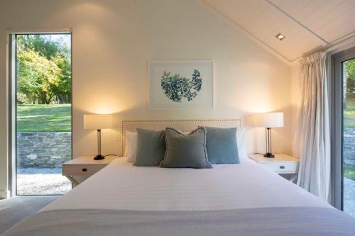 a bedroom with a large white bed with two lamps at Arrow Wood - Minutes to Arrowtown, Golf and Wineries - Luxury Living in Arrowtown