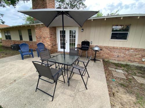 a table and chairs with an umbrella on a patio at Spacious Ranch Home Near Airport in Pensacola