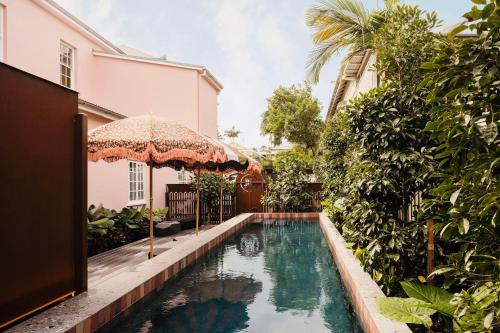 una piscina all'aperto con ombrellone accanto a una casa di Miss Midgley's - Refectory a Brisbane