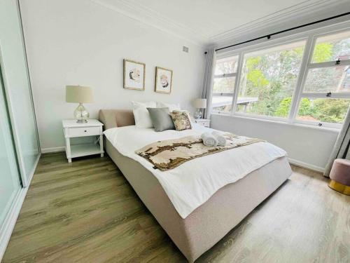una camera da letto bianca con un letto grande e una finestra di Renovated charming & cozy house (Walk to Station) a Sydney