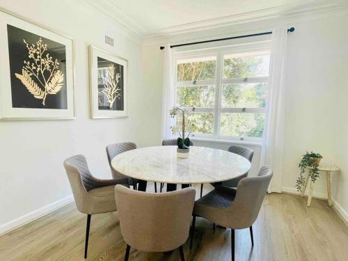 a dining room with a table and chairs and a window at Renovated charming & cozy house (Walk to Station) in Sydney