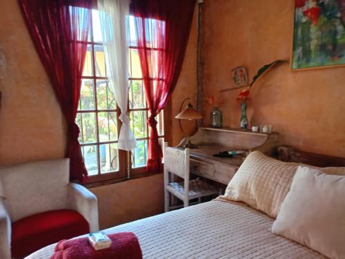 a bedroom with a bed and a desk and a window at Vila Santa Rosa Guest House in Ilhabela