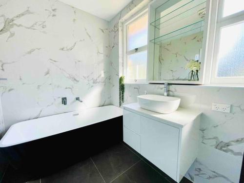 un bagno bianco con vasca e lavandino di Renovated charming & cozy house (Walk to Station) a Sydney