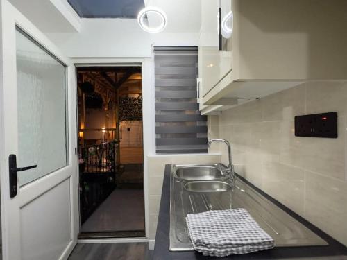 een keuken met een wastafel en een deur naar een trap bij Gorgeous Graceful Getaway w/ Gazebo - Tylorstown in Llwyn-y-pia