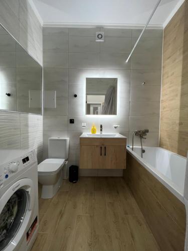 a bathroom with a tub and a sink and a washing machine at Grand Champion Astana in Taldykolʼ